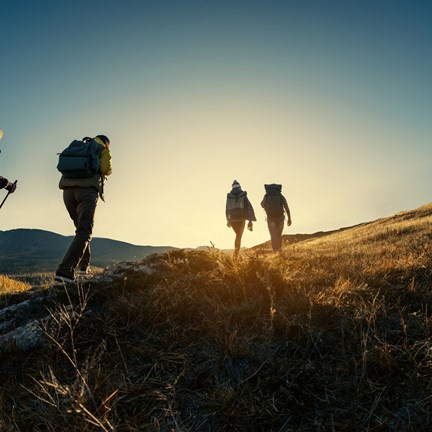 Group of four hikers, walking up a mountain in England at sunset